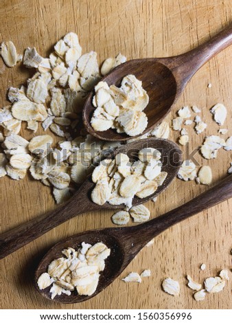 Rollet oats in wooden spoons on wood table ,vertical image.