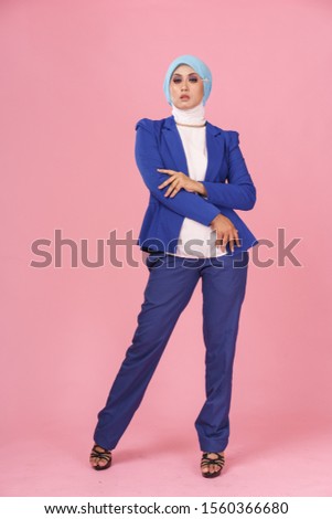 Beautiful elegance muslim lady , clothed in blue business suit, white cotton blouse with hijab isolated over pink background.  Woman business corporate concept.