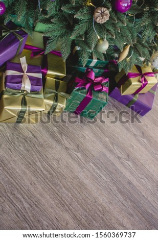 Stylishly wrapped purple golden and green gifts under the Christmas tree. New Years Eve Celebration. Up view