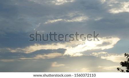 Golden sunlight reflects beautiful floating gray clouds. Right corner with trees