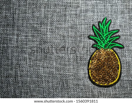 Plain gray ribbed fabric. Pineapple from sequins. Uniform cotton background. Thick canvas. Vintage burlap. Threads made of wool.