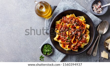 Pasta fettuccine with beef ragout sauce in black bowl. Grey background. Copy space. Top view. Royalty-Free Stock Photo #1560394937
