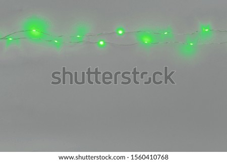 Green color illuminated garland on light gray background
