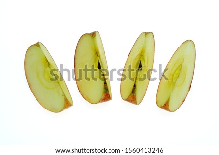 Red apples that are cut into pieces placed on a white background, taken with a macro lens.                    