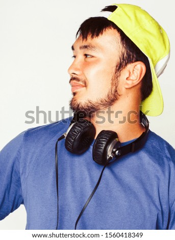 young asian man in hat and headphones listening music on white background