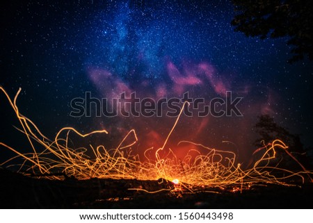 Bright bonfire sparks under starry sky