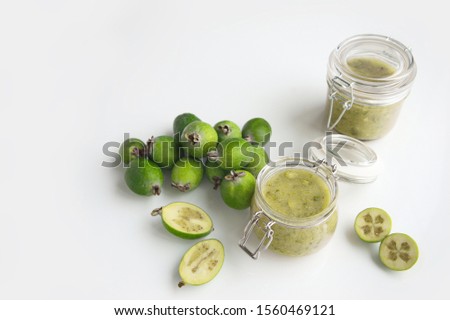 whole feijoa fruits and a section, rubbed feijoa in a glass jar on a white background