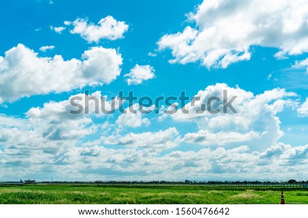 Landscape green grass field and wire fence of the airport and beautiful blue sky and white fluffy clouds. Nice weather. Nature landscape. Area around the airport. Fence for safety.