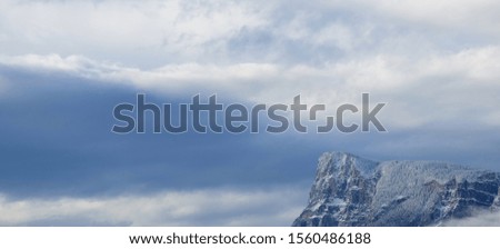Dark clouds in the evening sky in front of snowy mountains in the Alps