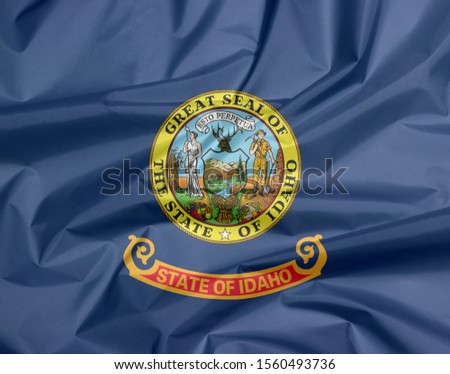 Fabric flag of Idaho. Crease of Idaho flag background, the states of America. State seal of Idaho on a field of blue.