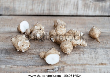 Root of topinabur on a wooden background. Jerusalem artichokes called sunroot.