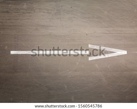 Flat lay picture of white arrow on a gray asphalt - Aerial drone top down view of white arrow on asphalt
