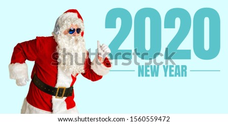 Santa Claus in sunglasses isolated on blue studio background. Caucasian male model in traditional costume. Concept of Christmas, 2020 New Year's, winter mood. Copyspace. Showing smartphone screen.
