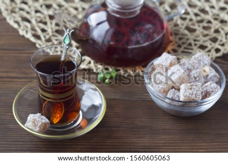 Turkish tea in a traditional glass cup and Turkish sweets on a wooden table.