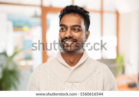 emotion, expression and people concept - smiling indian man in knitted woolen sweater over office background