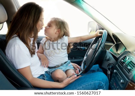 beautiful young woman holding her sweet daughter in her arms kissing in the car mother and daughter spend time together