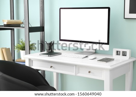 Comfortable workplace with modern computer near color wall