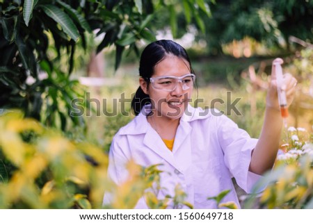 Asian woman researcher using syringe for examining and study information data in the garden,Selective focus