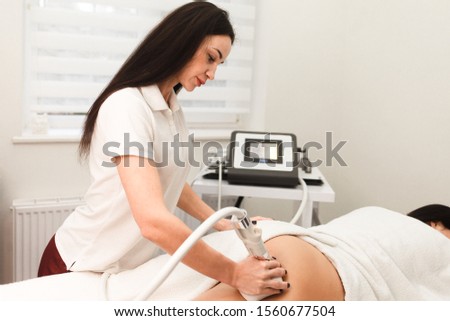 Doctor cosmetologist with a roller in his hands makes a buttocks massage with device