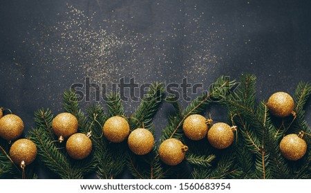 A frame of green fir and Christmas toys on a black background with empty space. Top view!