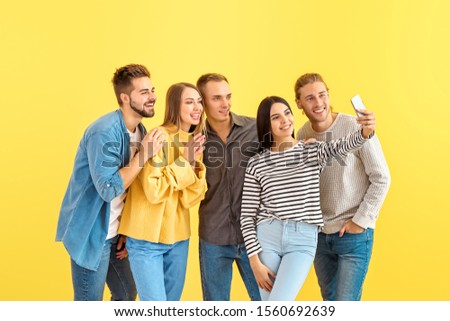 Group of friends taking selfie on color background