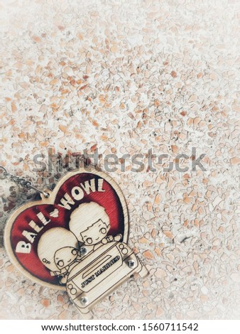 Cartoon key ring. Woman and man sitting in the car with heart backdrop. Placed on the table.