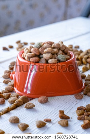 Fresh and natural dry pet food in a orange plastic bowl.