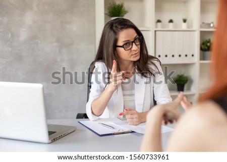 Boss has private conversation with her worker in her cabinet. Selective focus