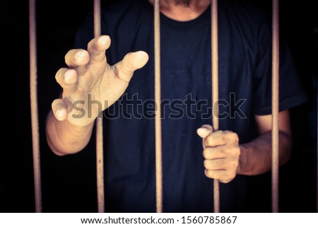 hand man reach out and hold steel in jail on black background.concept for prisoner,sadness,detain,erroneousness