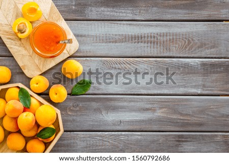 Summer preserves. Apricot jam in jar near fresh fruits on dark wooden background top view frame space for text