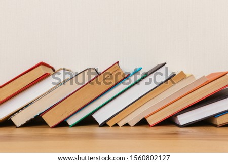Simple composition of many hardcover books, raw of books on a wooden table and a light background. I'm going back to school. Copy space Education.