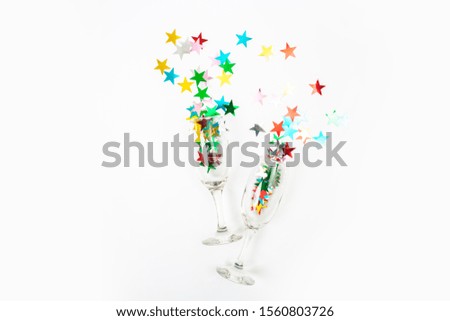 Glass of champagne with glitter on a white background, top view. Fun party. New Year or Christmas