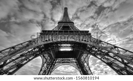 A grayscale low angle shot of the historic Eiffel tower under the gloomy sky