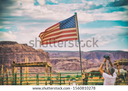 Male photographer taking pictures of american flag in the national park.