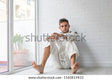 smiling young man sitting at home with sportswear