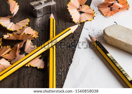 some pencils pencil shavings a sheet of paper and an eraser placed on brown wood table surface texture 