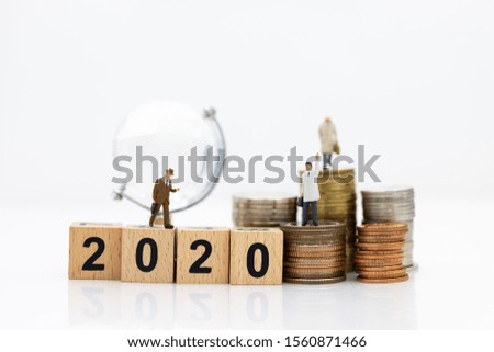 Miniature people: Businessman standing with stack of coins and wooden block 2020. Image use for investment for benefit of year, business concept.