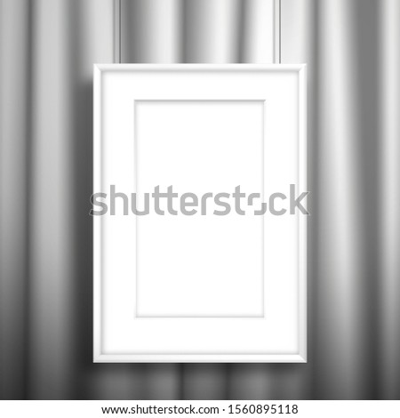 Blank white frame with passe-partout for an image or poster hanging on threads near the white curtain. Mockup for design