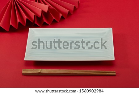 Chinese style chopsticks with red background and red folding fan, light green long plate and bamboo modeling