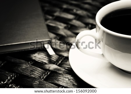Coffee cup on a wicker table with a notebook aside. Breakfast concept