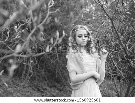 
young beautiful girl in a light lilac dress in the garden where magnolias bloom