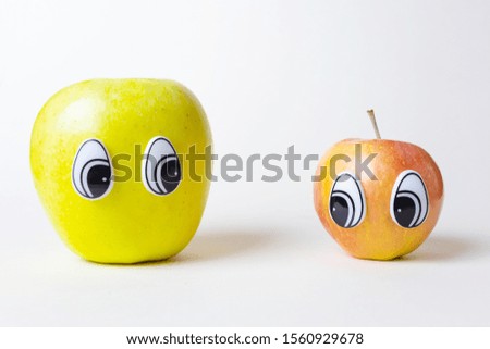 Red and green apple with eyes. Apples are looking at each other. Funny cute pictures of fruits. The concept of friendship, sympathy, love. Light background, place for text.