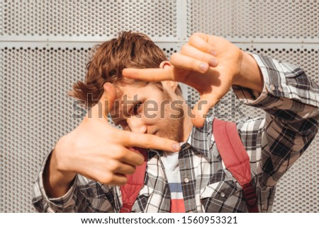 young happy man framing photograph with fingers to make photo