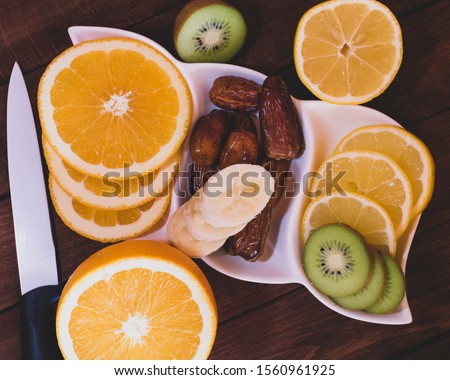 Tropical fruit mix and extra pitted dates on wooden table