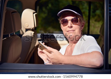 Young woman sitting in the car with hat using a phone
