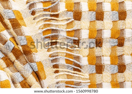 Knitted Plaid with Fringe Background. Knitwear Blanket Fabric Texture with a Complex Square Interweaving.