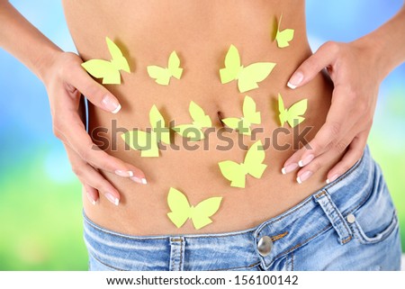 Butterfly on stomach on light background