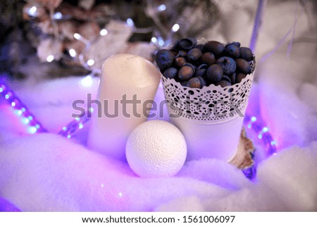 Christmas scenery white candle on the side and snow ball near white bucket with acorns