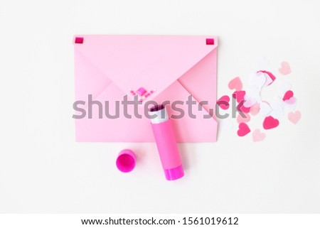 Pink envelope decorated with rhinestones, glue, confetti hearts on white background. Making postcard in envelope for Valentine's Day. Do it yourself. Photo from the series