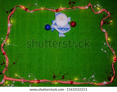 Christmas background. Dark green background in a frame of red and white hearts, beads with lights. In the middle is Santa Claus with Christmas tree toys.